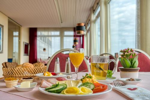 a table with plates of food and glasses of orange juice at FF&E Hotel Dania in Puttgarden