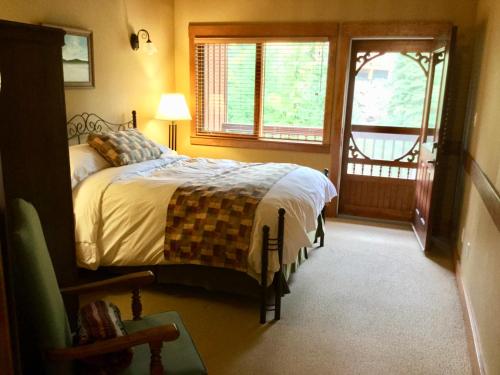 1 dormitorio con cama, ventana y puerta en Vagabond Lodge at Kicking Horse, en Golden