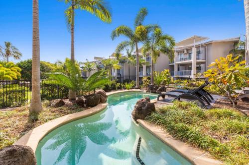 a swimming pool in front of a building with palm trees at Resort Rooms at Bells Boulevard in Kingscliff