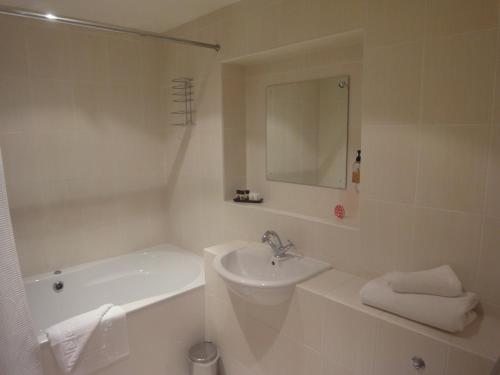 a white bathroom with a sink and a bath tub at The Treebridge Hotel in Nunthorpe