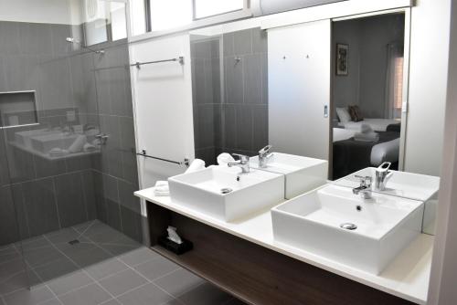 a bathroom with two sinks and a shower and a mirror at River Motel in Barham