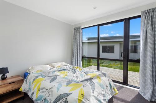 a bedroom with a bed and a large window at Kukumoa At the Beach in Opotiki