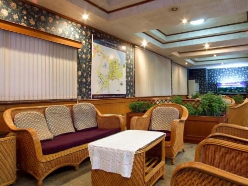 una sala de espera con sillas de mimbre y una mesa en Sakol Grand Palace en Sakon Nakhon