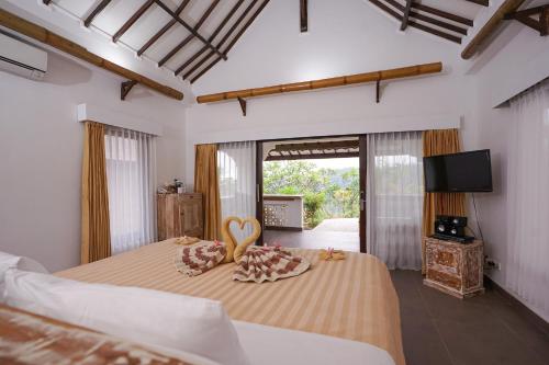 a bedroom with two beds and a television and a bed with two pillows at Rinjani Lodge in Senaru