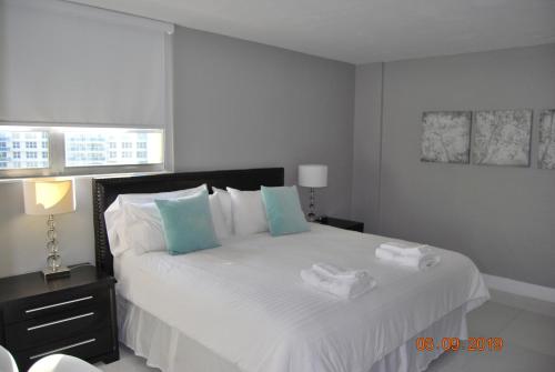 a bedroom with a large white bed with towels on it at The Tides Apartment in Hollywood