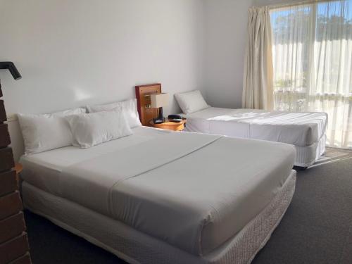 a hotel room with two beds and a window at Matador Motor Inn in Coffs Harbour