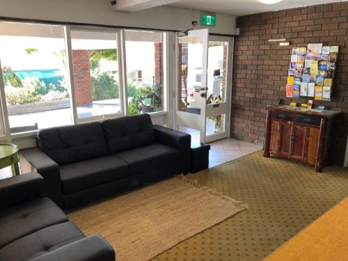 a living room with a black couch and a brick wall at Matador Motor Inn in Coffs Harbour