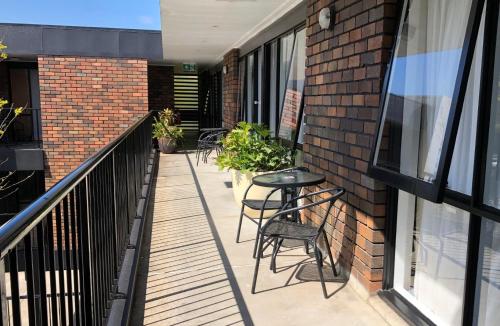 a balcony with chairs and tables on a brick building at Matador Motor Inn in Coffs Harbour