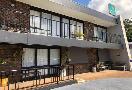 a building with a balcony with tables and chairs at Matador Motor Inn in Coffs Harbour