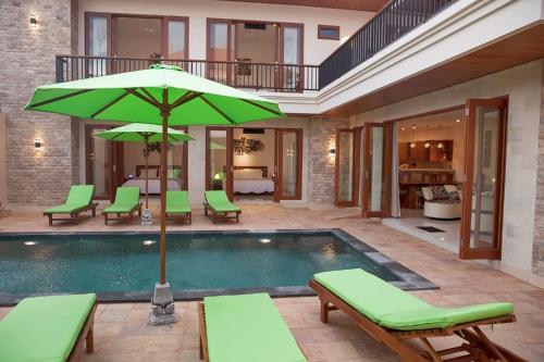 a swimming pool with a green umbrella and chairs at Pineapple Villa Sanur in Sanur