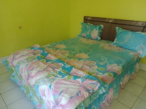 a bed with a colorful comforter and pillows at Bukit Senaru Homestay in Senaru