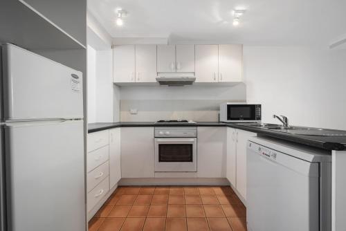 a kitchen with white cabinets and white appliances at Avoca Beach Hotel in Avoca Beach