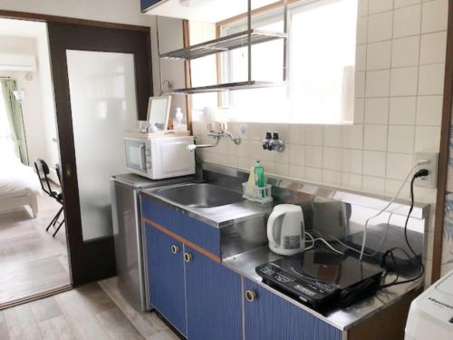 a small kitchen with a sink and a microwave at Rapport Kukomae 207 in Fukuoka