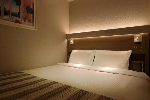 a bed in a hotel room with lights on it at Keio Presso Inn Otemachi in Tokyo