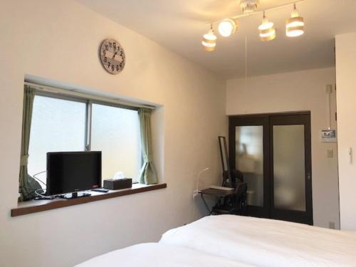 1 dormitorio con 1 cama y reloj en la pared en Rapport Kukomae 207 en Fukuoka