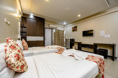a hotel room with two beds and a desk at Gold Airport Suites in Lat Krabang