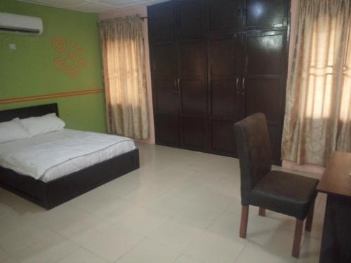 - une chambre avec un lit, une chaise et un bureau dans l'établissement Tiffany Apartments, à Ibadan