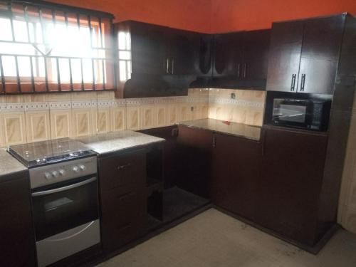 cocina con armarios negros y horno con fogones en Tiffany Apartments, en Ibadán