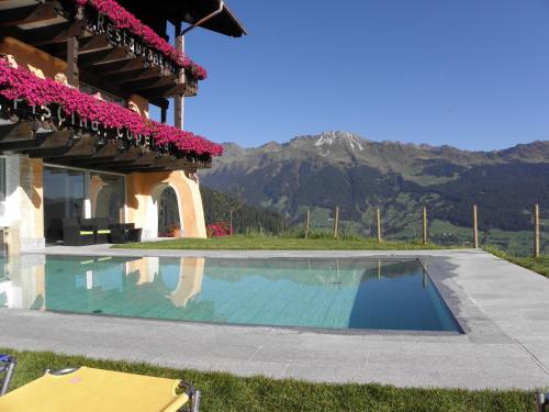 a swimming pool in front of a house with a mountain at Sporthotel Kalcherhof in Racines