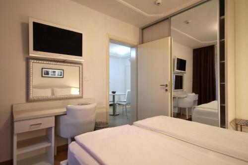 a hotel room with a bed and a desk and a mirror at Hotel Aruba in Budva