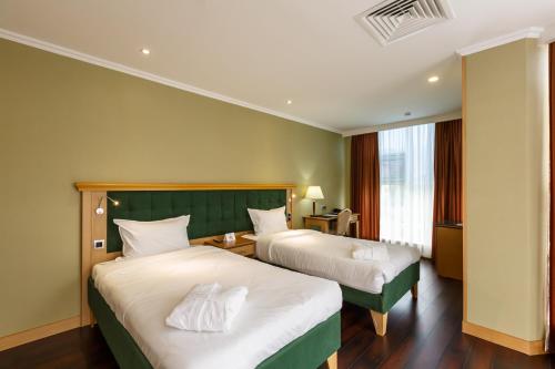 a hotel room with two beds and a window at Shera Park Boutique Hotel in Almaty
