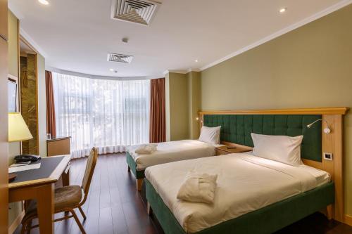 a hotel room with two beds and a desk and a desk at Shera Park Boutique Hotel in Almaty