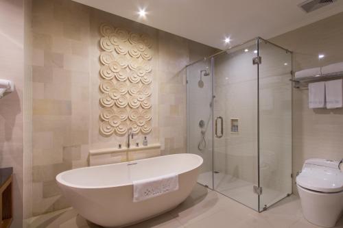 a bathroom with a tub and a shower and a toilet at Adhi Jaya Hotel in Kuta