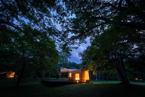 a small tent in a park with trees at night at Snow Peak Jyubako（AKAIGAWA TOMO PLAYPARK） in Akaigawa