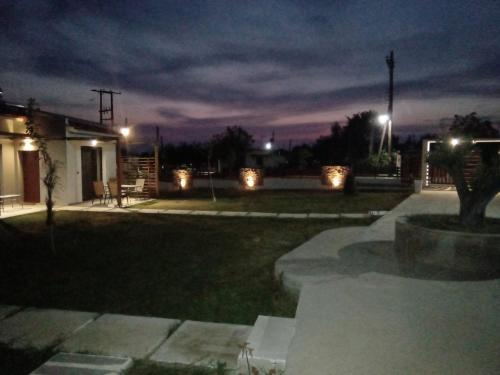a yard at night with lights on a house at Hill Sun Luxury Suites in Nea Iraklia