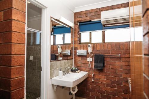 a bathroom with a sink and a brick wall at Country Pathfinder Motor Inn in Dalby