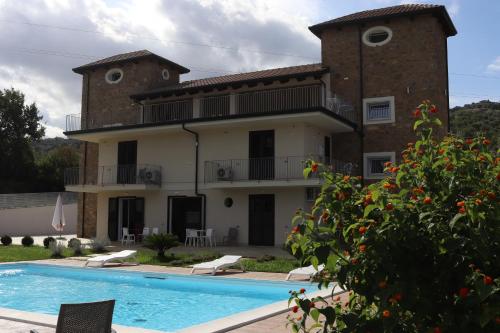 a villa with a swimming pool in front of a house at LE TORRI DEL CILENTO in Santa Maria di Castellabate