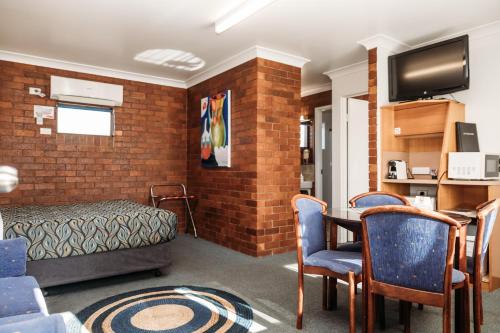 a room with a bed and a table and chairs at Country Pathfinder Motor Inn in Dalby