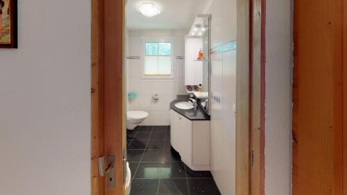 La salle de bains est pourvue de toilettes blanches et d'un lavabo. dans l'établissement Mara MA3, à Blatten bei Naters
