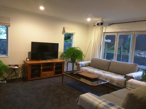 a living room with a couch and a flat screen tv at Stay Auckland in Auckland