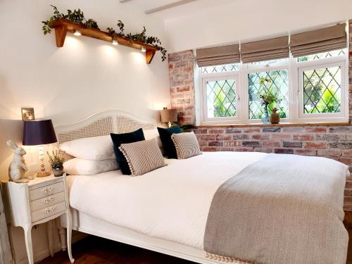 a bedroom with a white bed and a brick wall at Owl Lodge in Newport Pagnell