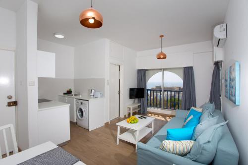 a living room with a blue couch and a kitchen at White Arches Apt #1 by TrulyCyprus in Limassol