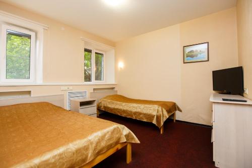 a hotel room with two beds and a flat screen tv at Aurinko in Petrozavodsk