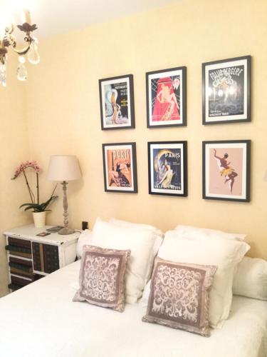 een slaapkamer met een wit bed met ingelijste foto's aan de muur bij Le Grand Appartement in Sainte-Foy-la-Grande