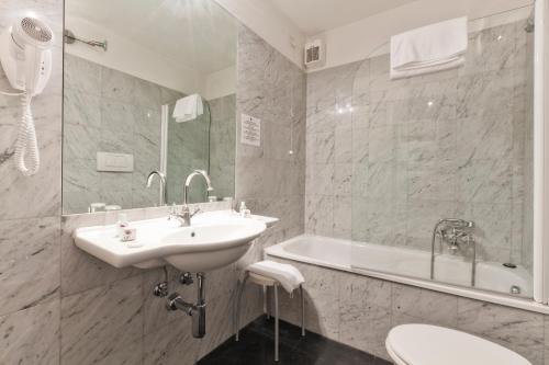 La salle de bains blanche est pourvue d'un lavabo et d'une baignoire. dans l'établissement Palazzo Cendon Piano Antico, à Venise