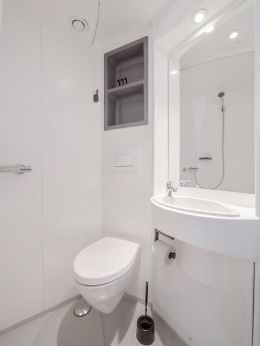 a white bathroom with a toilet and a sink at Hamnhotellet in Västervik