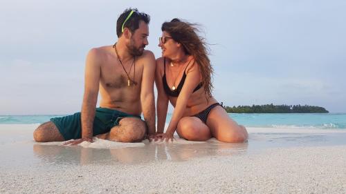 a man and a woman sitting on the beach at Finimas Residence in Thimarafushi