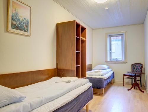 a room with two beds and a cabinet and a chair at BB-Hotel Frederikshavn Turisthotellet in Frederikshavn