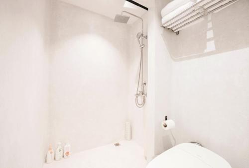 La salle de bains blanche est pourvue d'une douche et de toilettes. dans l'établissement Hang Zhou Peach Guesthouse, à Hangzhou