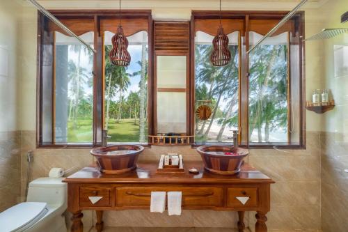 two sinks in a bathroom with a window at Coco Palm Beach Resort & Spa in Phú Quốc