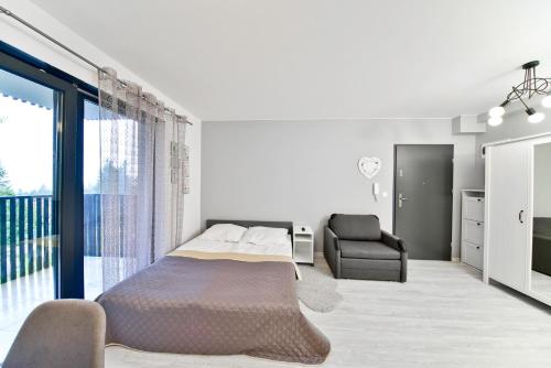 カルパチにあるApartament Szarotka - Apartamentujの白いベッドルーム(ベッド1台、椅子付)