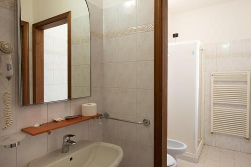 uma casa de banho com um lavatório, um espelho e um WC. em Hotel Fattori em Bolonha
