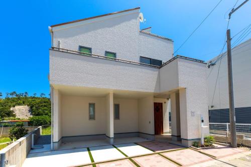 a white building with a balcony on top at Okinawa Seaside Besso5 in Onna