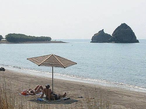 two people laying on the beach under an umbrella at Katsaraki Fotini in Mirina