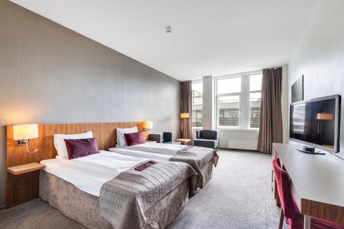 ein Hotelzimmer mit einem großen Bett und einem Flachbild-TV in der Unterkunft Quality Hotel Residence in Sandnes