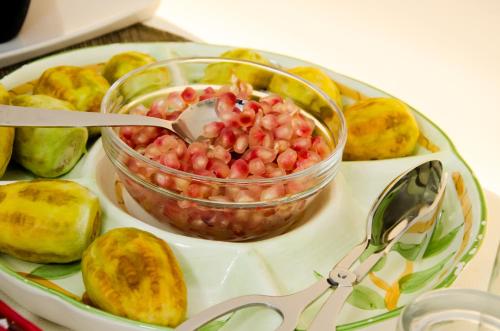 a plate of food with a bowl of fruit and a pair of scissors at Hotel Vittorio Veneto in Ragusa
